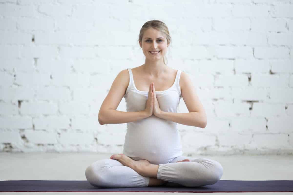 Pregnant young woman sitting prenatal yoga prayer position (1)